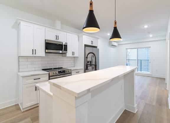 A kitchen with white cabinets and a white island.