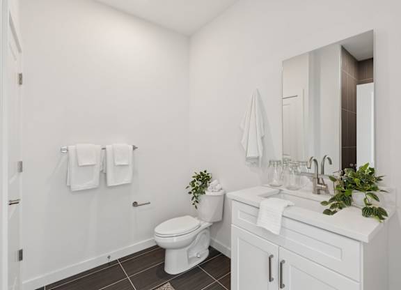 A white bathroom with a toilet, sink, and mirror.