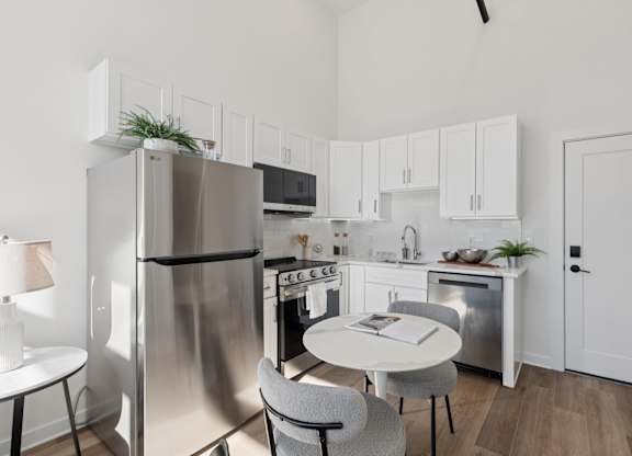 A modern kitchen with a white table and grey chairs.
