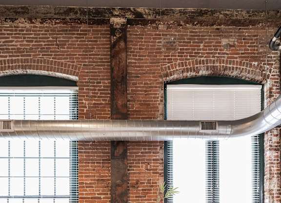 A white couch sits in a room with a brick wall and wooden floors.
