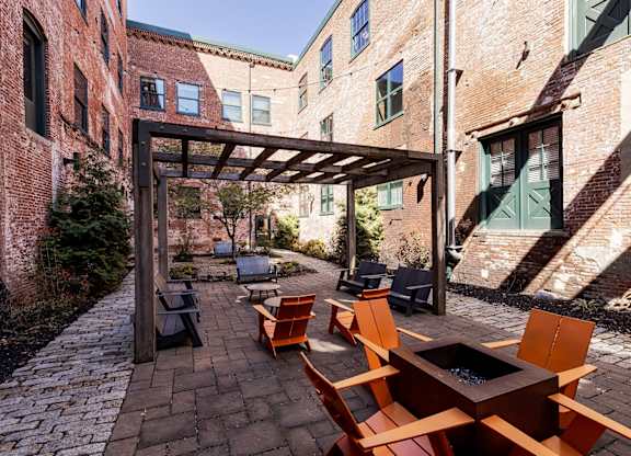 A patio with a fire pit and chairs.