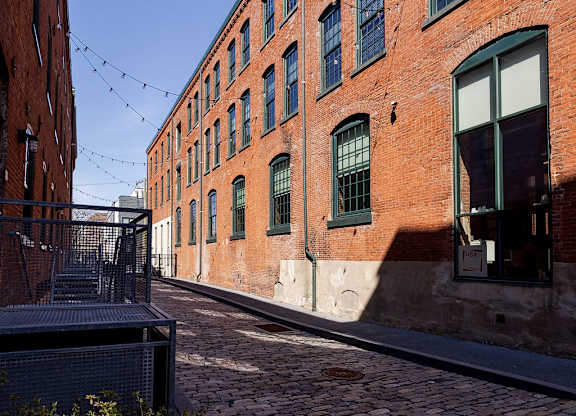 A brick building with green shutters and a metal gate.