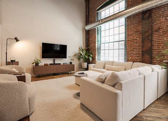 A living room with a white couch and a television on the wall.