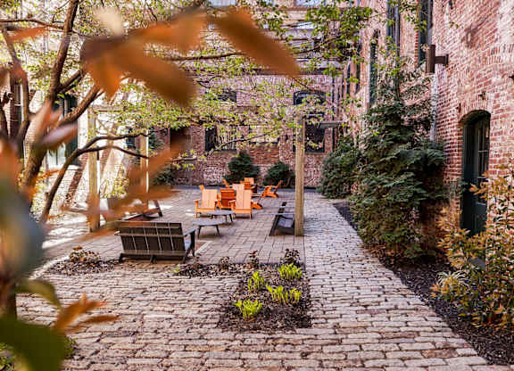 A brick pathway leads to a bench in a courtyard.
