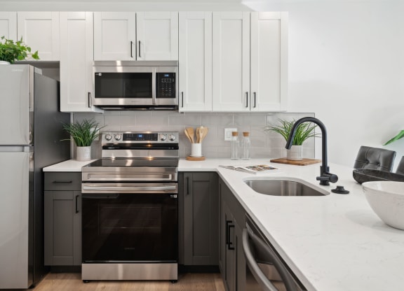Modern kitchen with stainless steel appliances and white cabinets at The Isaac, Philadelphia, 19122