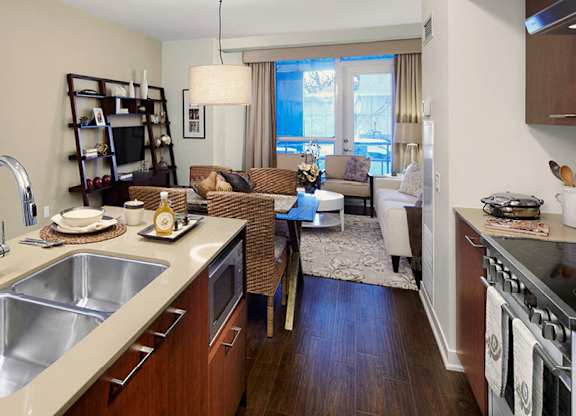 A kitchen with a sink, stove, and a dining table.