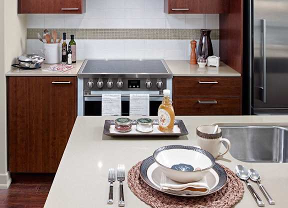 A modern kitchen with a stove, sink, and dining table set for two.