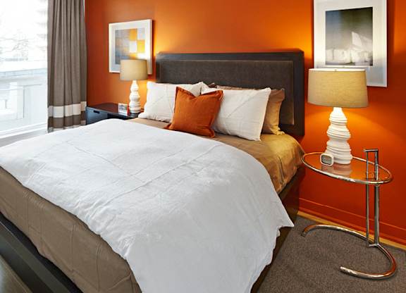 A bedroom with a large bed and a chair.