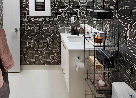 A bathroom with a white sink and a black and white tiled wall.