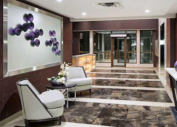A hallway with a glass wall and a brown wall with purple circles on it.