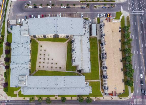 A large building with a green roof is surrounded by roads and other buildings.