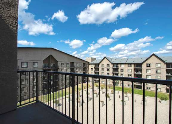 A balcony overlooks a courtyard with a building in the background.