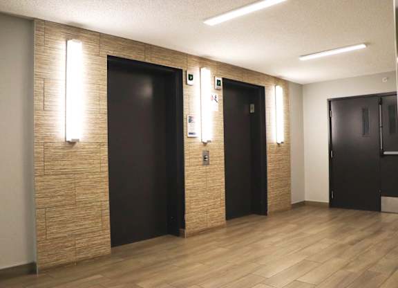 A hallway with wooden floors and two doors on the right.