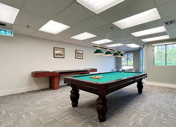 A pool table in a room with a bench and pictures on the wall.
