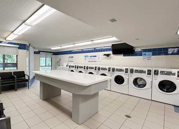 A laundry room with a washer and dryer on the wall and a table in the middle.