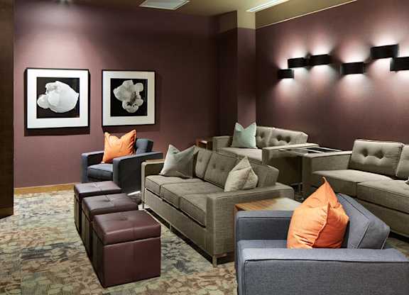 A theatre room with a grey couch and a brown ottoman.