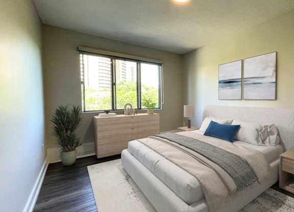 A bedroom with a large bed, a nightstand, and a plant.