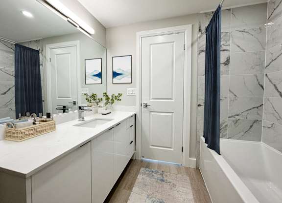 a white and gray bathroom with a shower and a sink