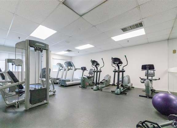 A gym with a variety of equipment including treadmills, stationary bikes, and weight machines.