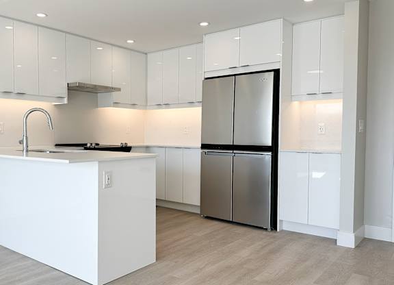 a kitchen with white cabinets and a stainless steel refrigerator