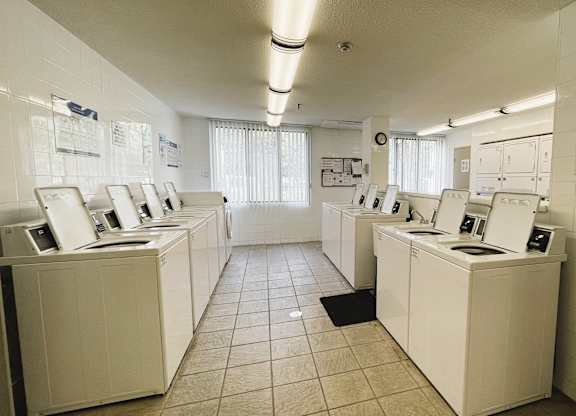 A laundromat with washers and dryers lined up.