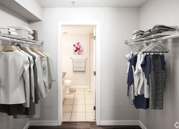 A white bathroom with clothes hanging on the rack.