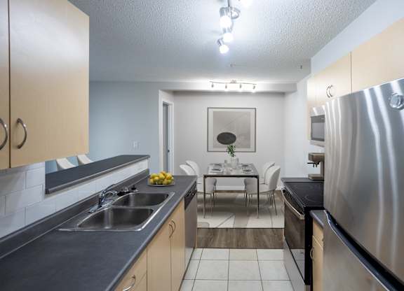 A modern kitchen with a stainless steel refrigerator, sink, and cabinets.