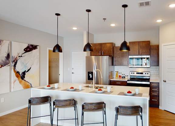 A kitchen with a white counter and bar stools.