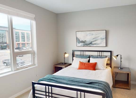 A bedroom with a bed, nightstands, and a painting on the wall.