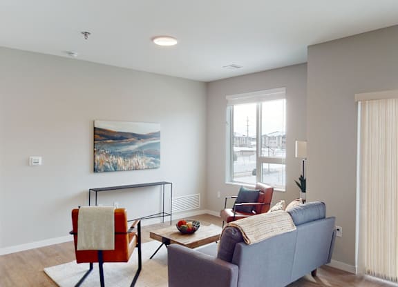 A living room with a blue couch, a red chair, and a painting on the wall.