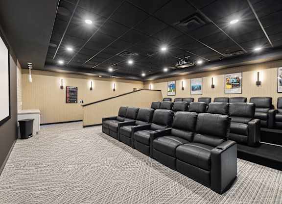 A large room with a carpeted floor and a row of black leather seats.