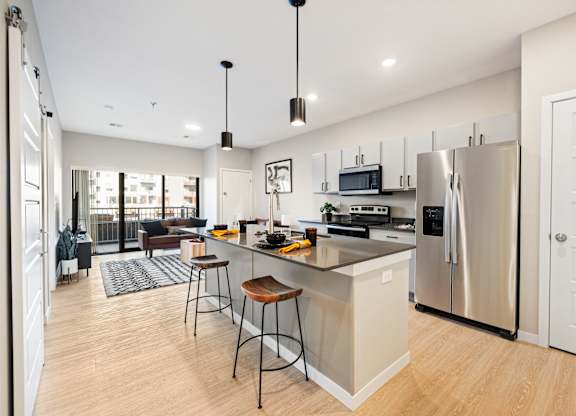 A modern kitchen with a bar stool and a refrigerator.