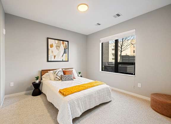 A bedroom with a bed, a small table, and a window.