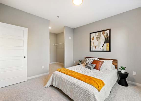 A bedroom with a bed, a painting, and a small table.