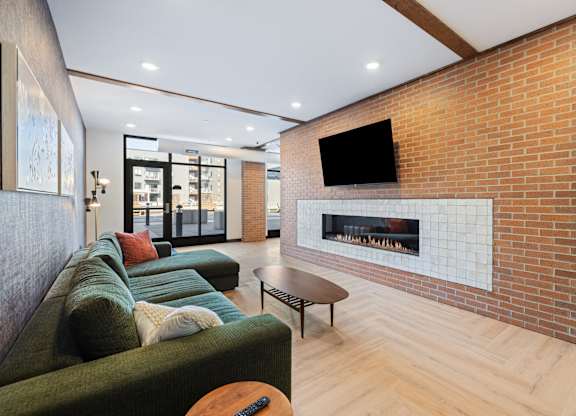 A living room with a green couch and a brick wall.