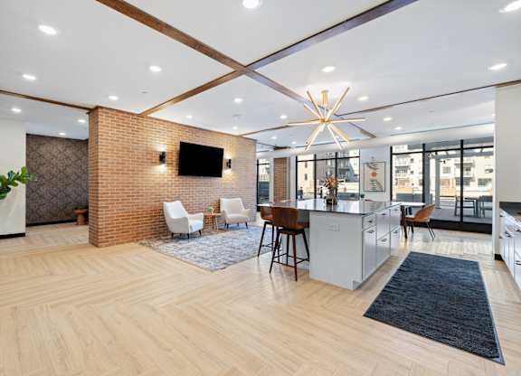 A modern kitchen with a wooden floor and a brick wall.