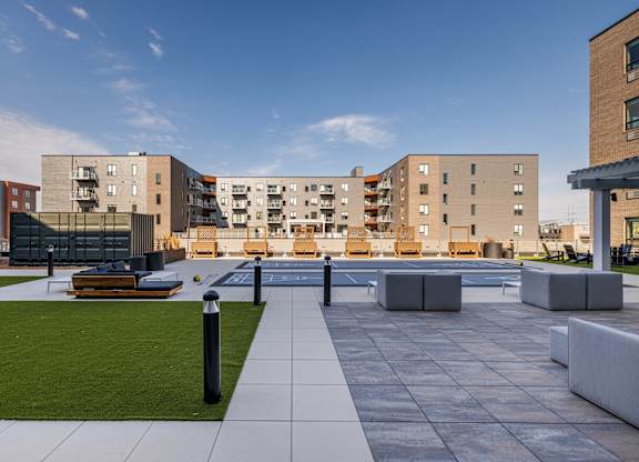A modern courtyard with a grassy area and benches surrounded by apartment buildings.