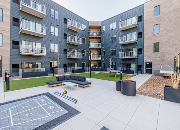 A tennis court is located in the courtyard of a modern apartment complex.