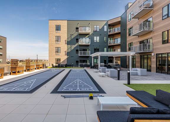 A rooftop with a bowling alley and benches in front of apartment buildings.