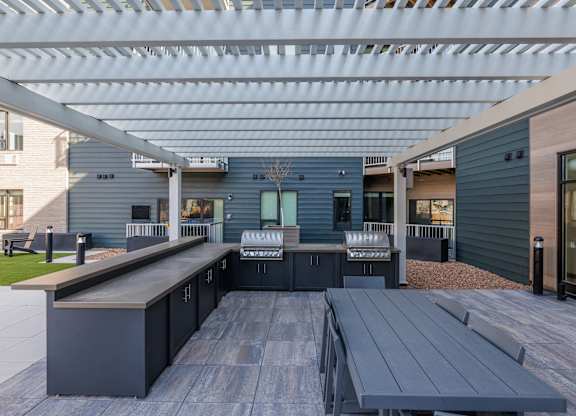 A modern outdoor kitchen with a long table and benches.