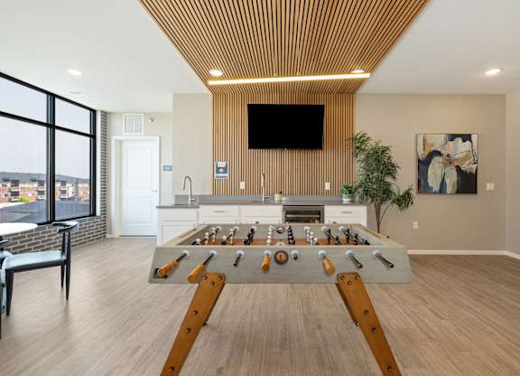 A foosball table in the middle of a room with a tv mounted on the wall.