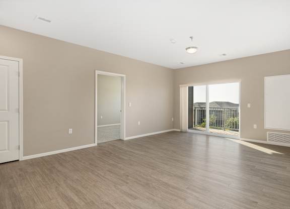 A large empty room with wooden flooring and white walls.