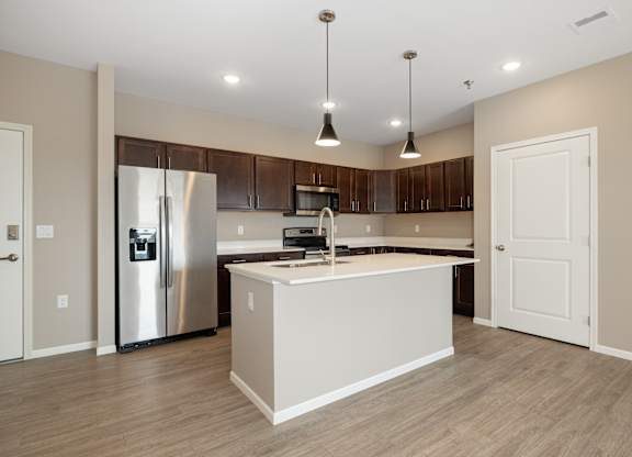A modern kitchen with a stainless steel refrigerator and wooden cabinets.