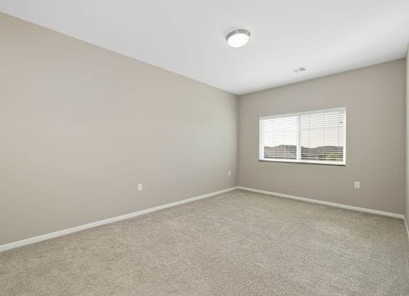 A room with a window and carpeted floor.
