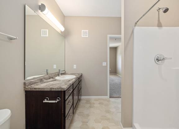 A bathroom with a marble countertop and a walk-in shower.