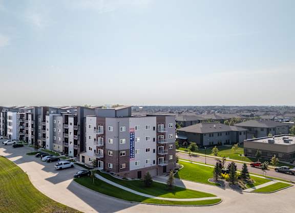A row of apartment buildings with a parking lot in front.