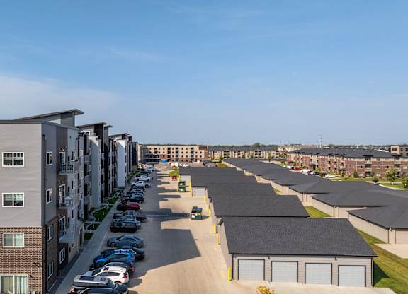 A row of modern apartment buildings with cars parked in the driveways.