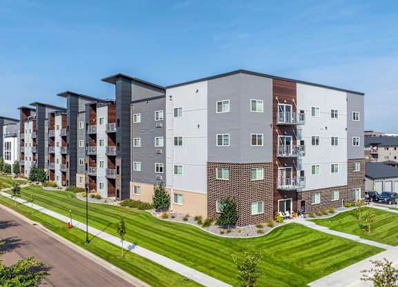 A row of modern apartment buildings with green lawns in front.