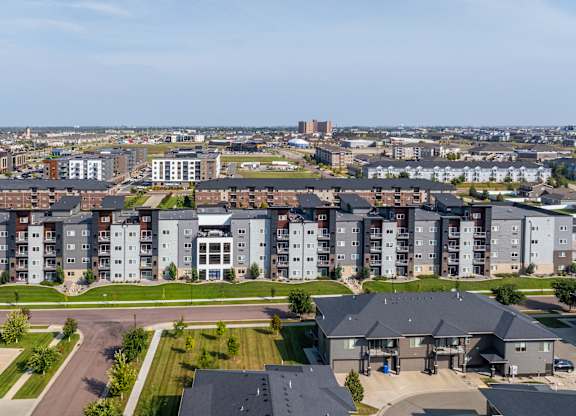 A large apartment complex with a parking lot in front.