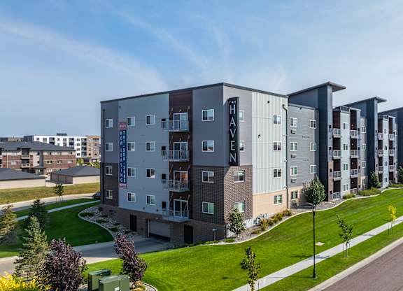 A long row of modern apartment buildings are lined up on a street.